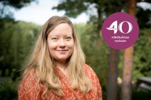 Elina Lauttamäki hymyilee kameralle oranssissa vaatetuksessaan.