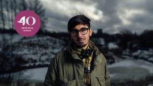 Adrian Perera katsoo kameraan lumisen talvisella maisemalla.